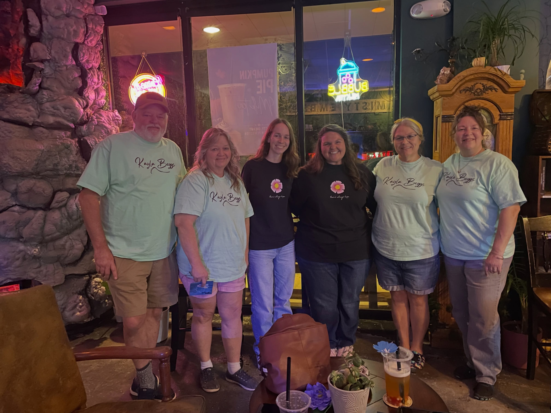 Six friends and family members together at Kayla Beggs' listening party, wearing Kayla's merchandise